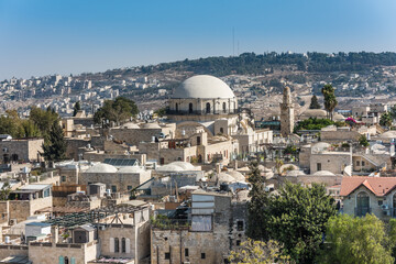 Naklejka premium Aerial view of rooftops of traditional buildings and Hurva Synagogue in the old city with blue sky of Jerusalem. View from the Lutheran Church of the Redeemer.