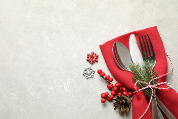 Cutlery set and festive decor on light grey table, flat lay with space for text. Christmas celebration