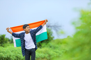 Cute little boy waving Indian National Tricolor Flag over nature background