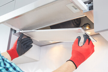 Male hands of an electrician troubleshoot a range hood. Cooker hood repair. Worker assemblying home...