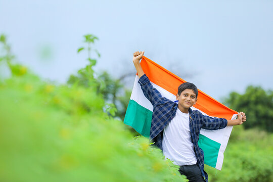 Cute little boy waving Indian National Tricolor Flag over nature background