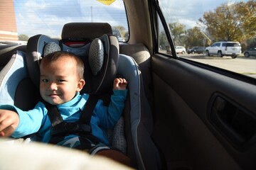 A cute asian toddler boy on the car seat in car