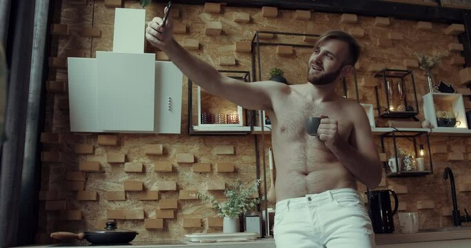 a young bearded boy serves morning coffee in his kitchen. Slow motion.