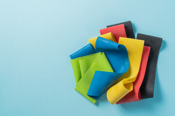 Home training concept - elastic bands on blue background, flat lay