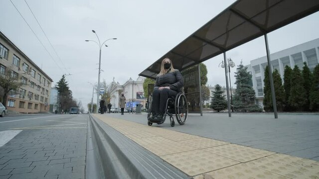Woman in a wheelchair waiting for a bus at a bus stop