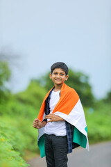 Cute little boy waving Indian National Tricolor Flag over nature background