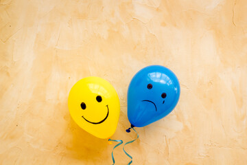 Emotions concept - happiness and sadness on the colored ballons. Top view - obrazy, fototapety, plakaty