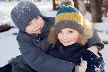 The boy laughs and hugs his brother on the street in winter.