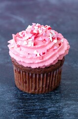 Muffin decorated with pink cream and hearts on a wooden background. Valentine's day gift. Romance. Red velvet cupcake.