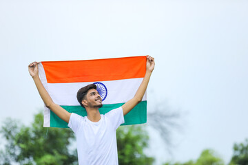 Young indian man waving indian national flag over nature background