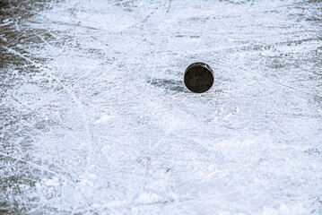 black hockey puck lies on ice at stadium