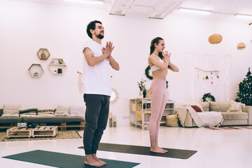Young happy couple practicing yoga together in living room