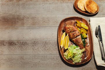 Baked red perch on a wooden dish with baked potato and lemon on wooden table background. Flat lay overhead view, seafood cooked composition mockup with copy space.