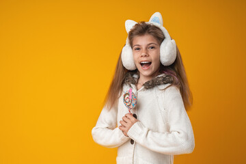 Happy girl holding Lollipop in hand, smiling happily stands on yellow background