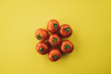 A group of red tomatoes on yellow background. Complimentary color style.
