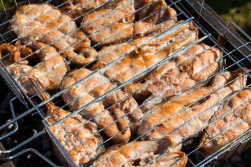 Top view of the browned steaks of red coho salmon fried on charcoal in a barbecue on a summer day in the country. Cooking a wholesome outdoor grill dinner.
