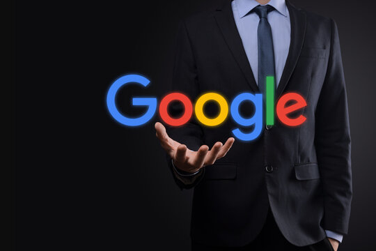 VINOGRADIV, UKRAINE - 30 DECEMBER 2020. Businessman in a suit on a dark background holds a Google logo inscription. Google is world's most popular search engine
