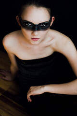 Young woman with makeup and a fashionable hairstyle poses in studio on black background