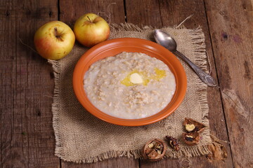Oatmeal with milk, nuts and apples on a wooden table