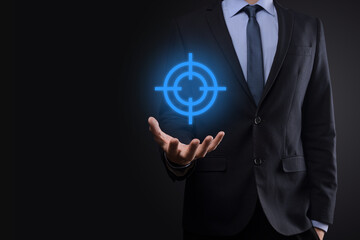 Targeting concept with businessman hand holding target icon dartboard sketch on chalkboard. Objective target and investment goal concept.