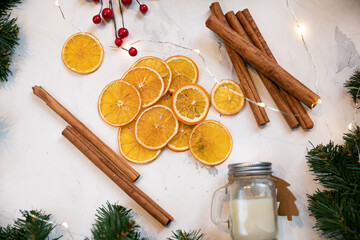 New year's still life. dried orange with cinnamon sticks, branches of the Christmas tree and a candle in a glass jar