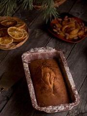 Cupcake in a baking dish, dried oranges, tangerines and Christmas tree branches in a basket on a wooden table. Country style.