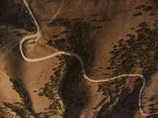 Aerial drone panorama shot of high mountain area, windmills, the long and winding road through the mountains. Southern region, sands, desert, birds eye view, sea shore on the background
