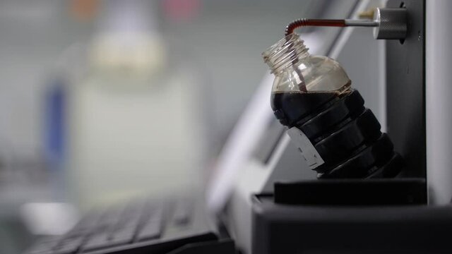 This video shows the lab technician's hand pushing a key on the keyboard, and then machine oil from a special bottle begins to flow into the analyzer.
