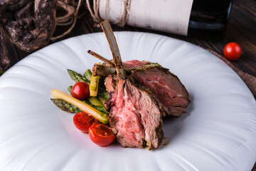 Lamb rack with provencal herbs on a large white plate.