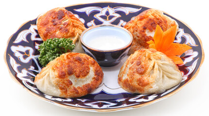 Uzbek manti with sour cream and herbs on a plate with an oriental ornament on a white background