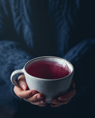 Woman hands holding a cup of red berry tea