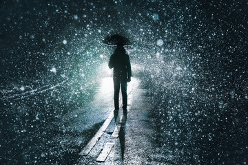 Silhouette of a man holding umbrella in the rain.  Night time backlit scene 