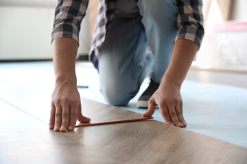 Fototapeta na wymiar Worker installing laminated wooden floor indoors, closeup