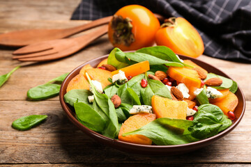 Delicious persimmon salad served on wooden table, closeup