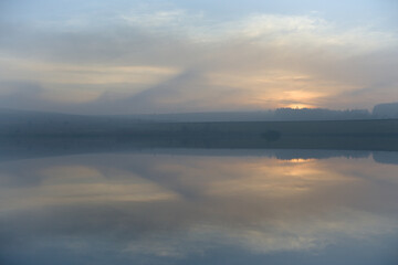 Obraz premium Abstract cloud formations at sunset reflected in still reservoir water