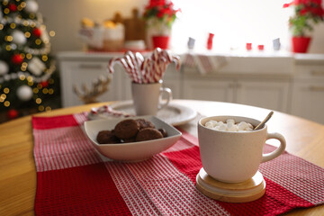 Delicious marshmallow cocoa on table in kitchen decorated for Christmas