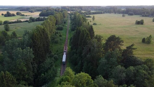 Narrow-gauge railroad train moving through country side landscape aerial view