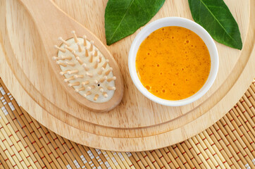 Fresh orange fruit mask (scrub) in a small white bowl and wooden hairbrush. Homemade face or hair mask, natural beauty treatment and spa recipe. Top view, copy space.