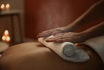 Obraz na płótnie Canvas Young woman receiving hot towel massage in spa salon, closeup
