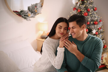 Happy couple near Christmas tree at home