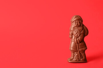 Sweet chocolate Santa Claus candy on red background, space for text