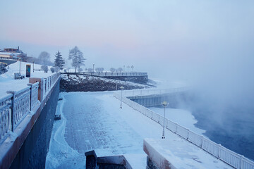 Foggy frosty morning. View of the winter embankment of the river. Urban landscape.