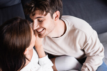Overhead view of smiling man looking at brunette girlfriend on couch
