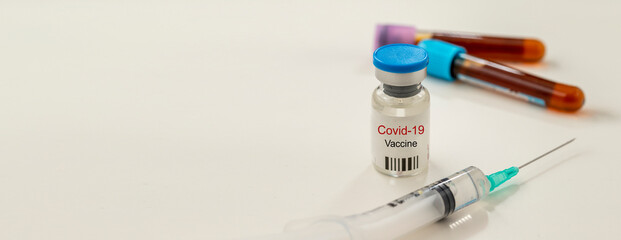 Coronavirus vaccine and syringe on a white background. with blood tubes at the back