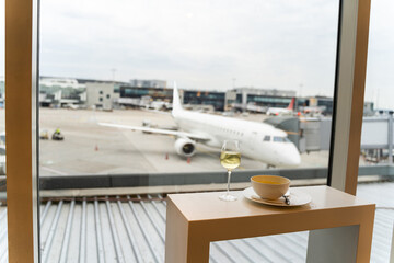 Glass of wine, bowl of soup near window with a view to airplane in airport