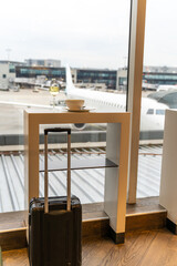 Glass of white wine, a bowl of soup and a black modern baggage in an airport