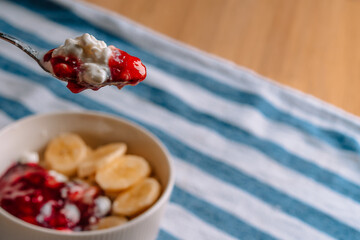 Cottage cheese with berry jam and bananas, spoon close-up