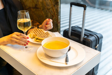 Woman having a drink with soup and sandwich in an airport restaurant