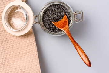 Dry poppy seeds in a glass jar on a blue background