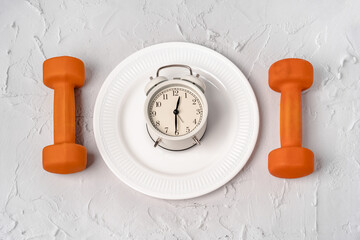 The alarm clock is on a plate and dumbbells as Cutlery